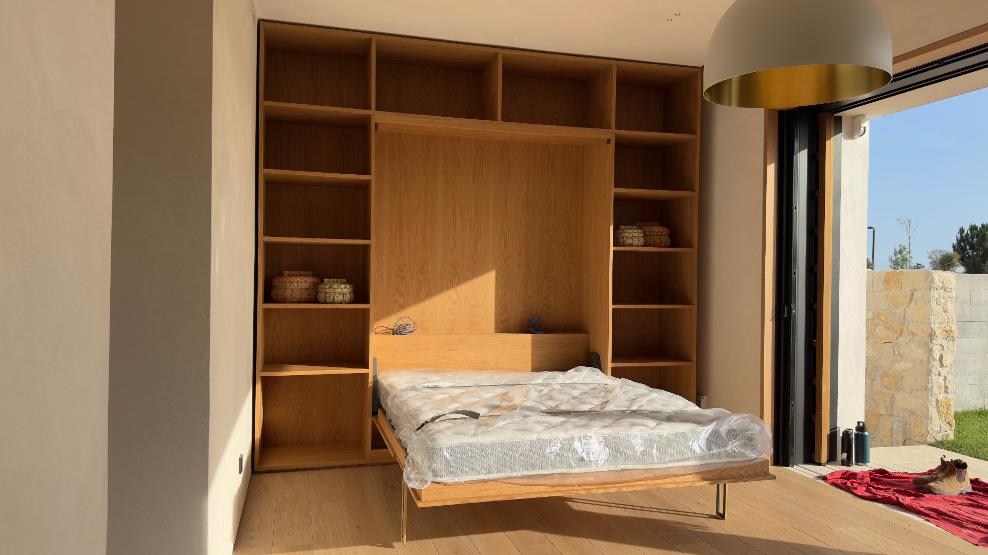 Oak murphy bed opened within fitted shelving wall